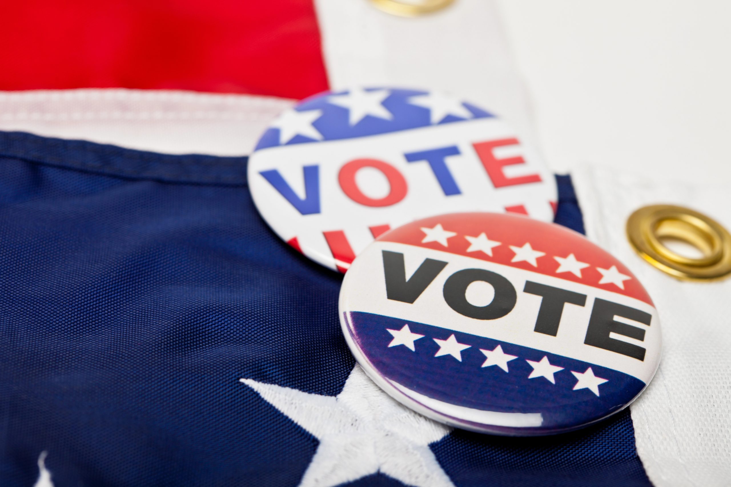 Vote buttons laying atop an American flag